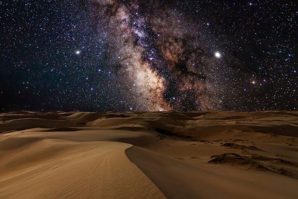 Vast sand dunes under a starry night sky